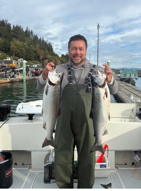 Captain Joe Miller holding a fresh salmon aboard his Seattle fishing charter boat on Puget Sound, guiding guests with All Star Fishing Charters.